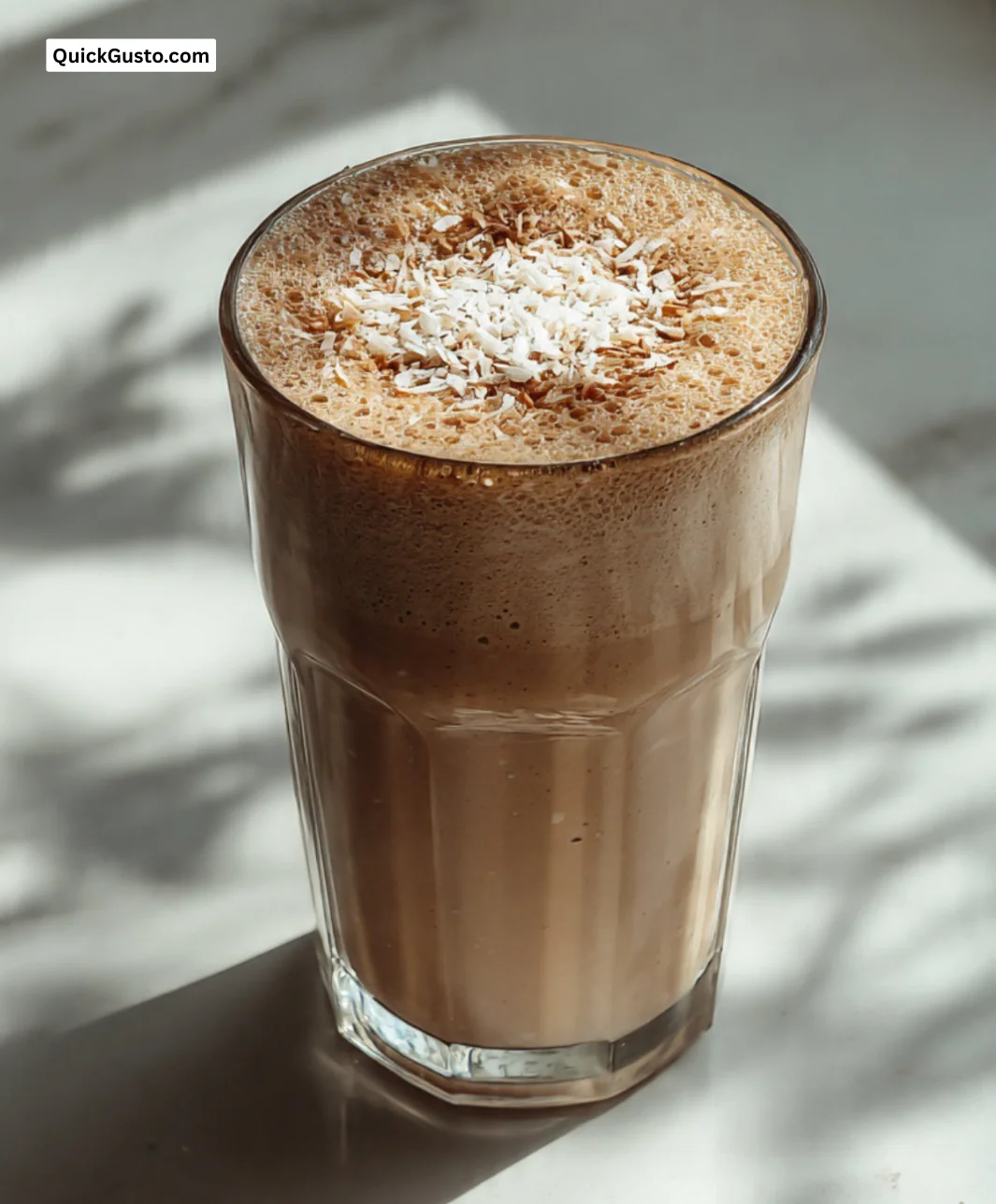Delicious Coconut Coffee Smoothie in a glass garnished with coconut flakes.
