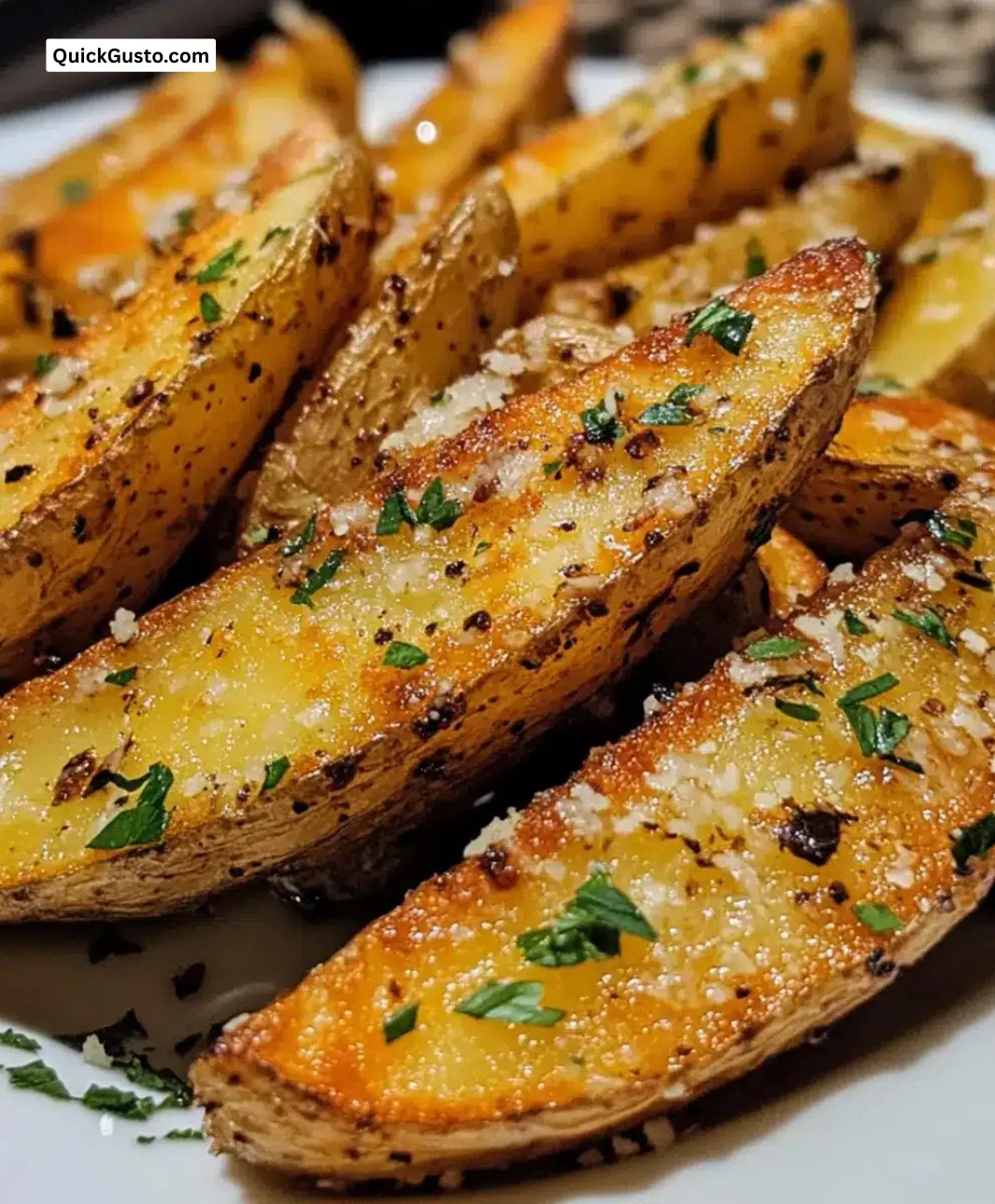 Crispy garlic parmesan potato wedges garnished with herbs on a wooden platter