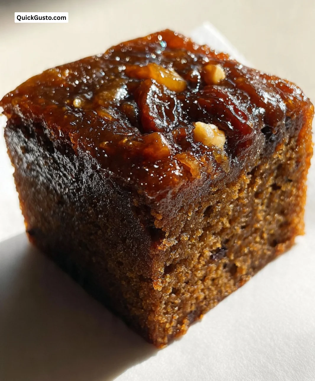 Delicious homemade Date Molasses Cake topped with nuts and served on a plate.