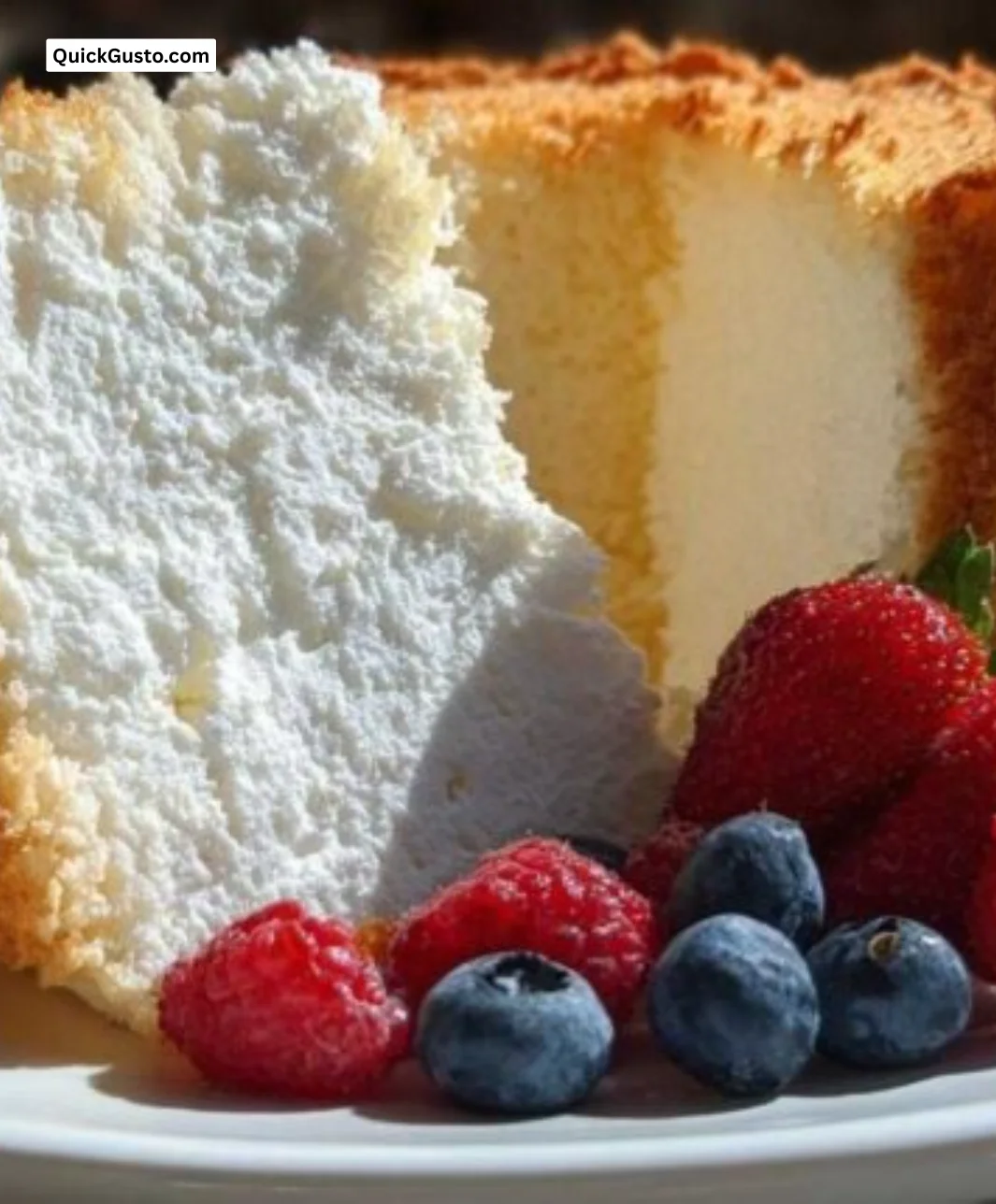 Slice of divine angel food cake topped with fresh berries and whipped cream