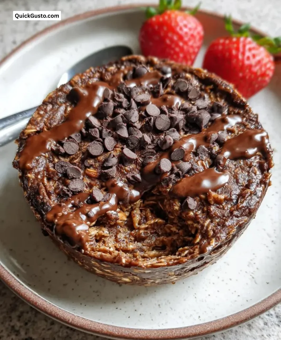 Bowl of fudgy chocolate baked oats topped with chocolate chips and berries