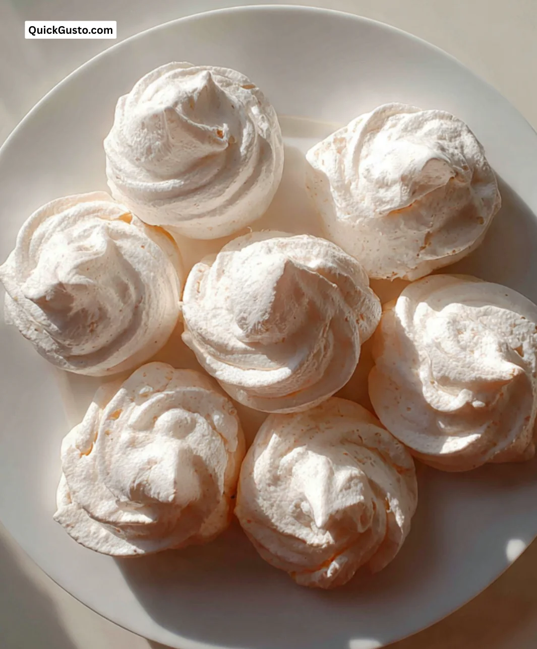 Delicious homemade meringue cookies on a decorative plate.