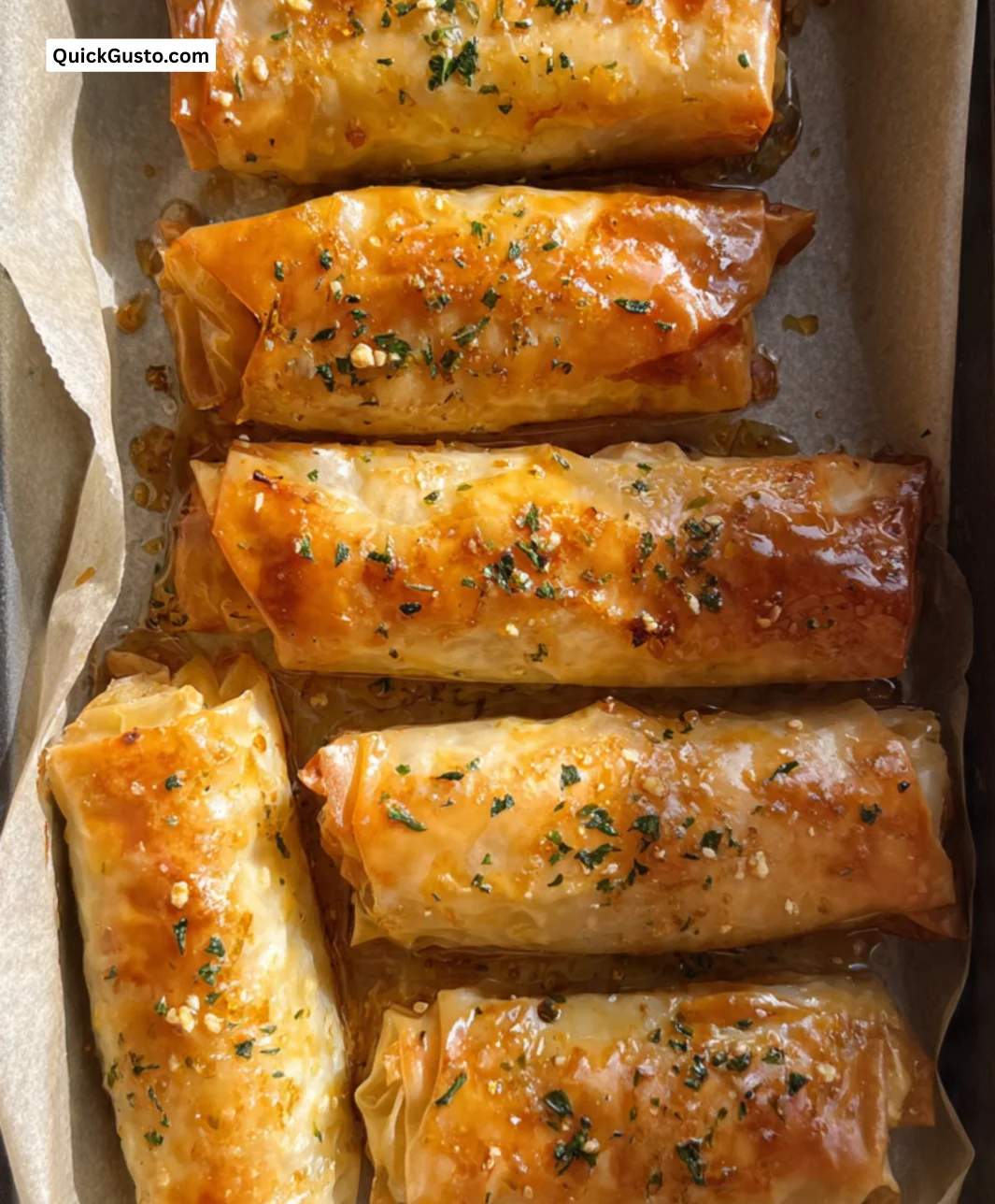 Oven fried feta rolls with chili honey and spices on a white plate