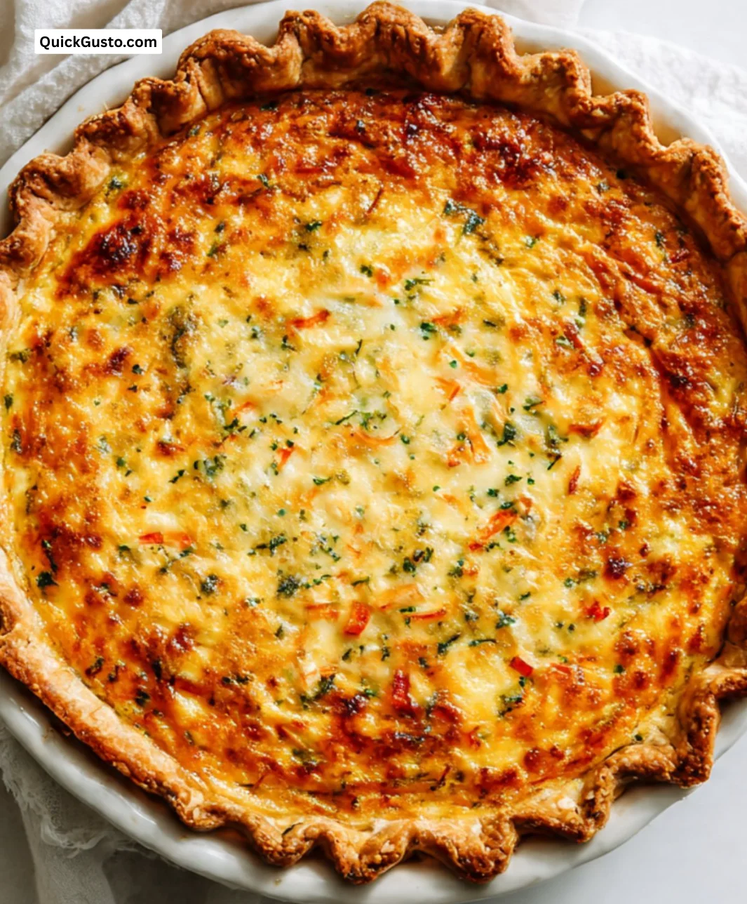 Delicious slice of perfect quiche with colorful vegetables and herbs on a plate.