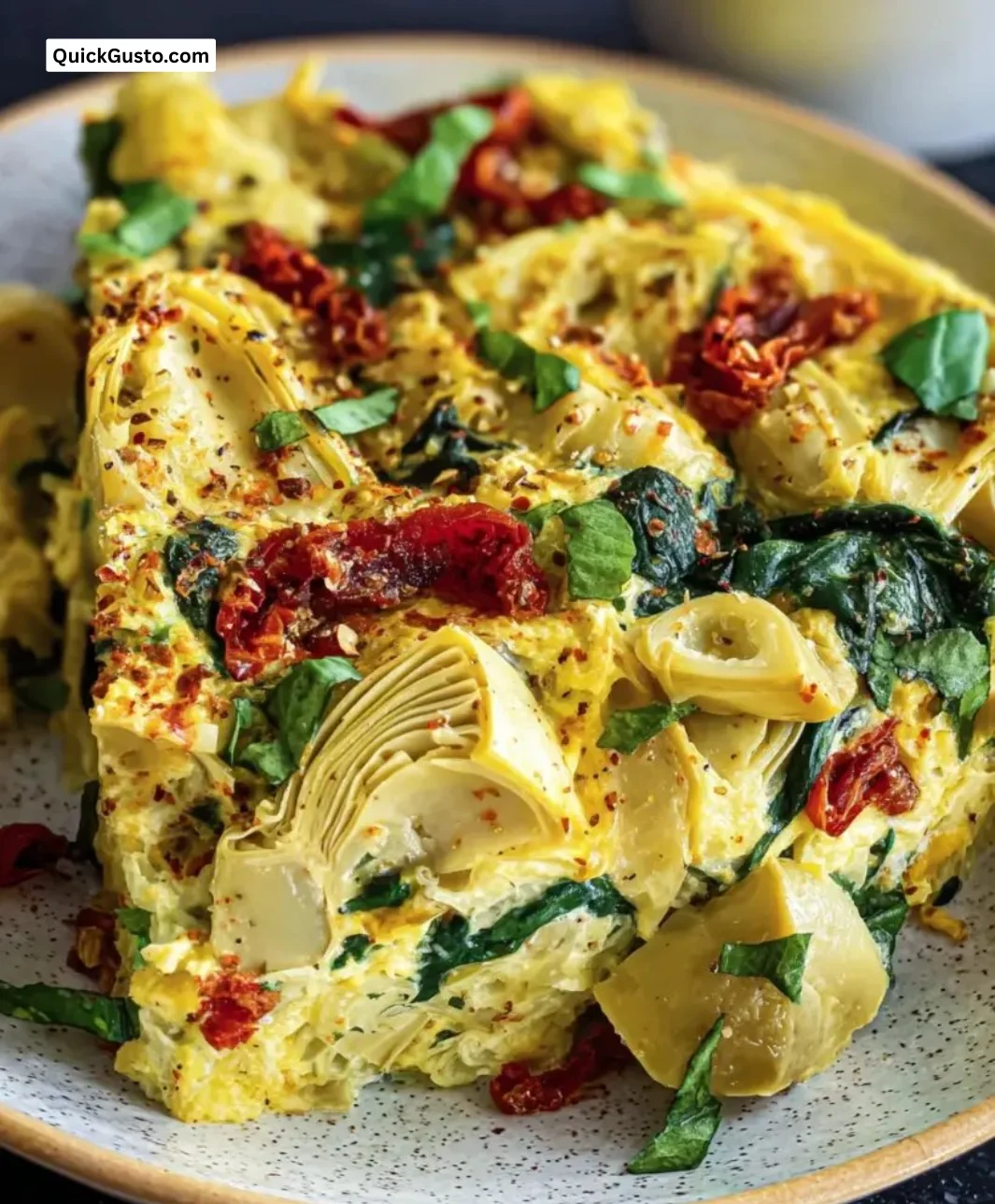 Delicious Spinach Artichoke Tomato Casserole topped with cheese in a baking dish.
