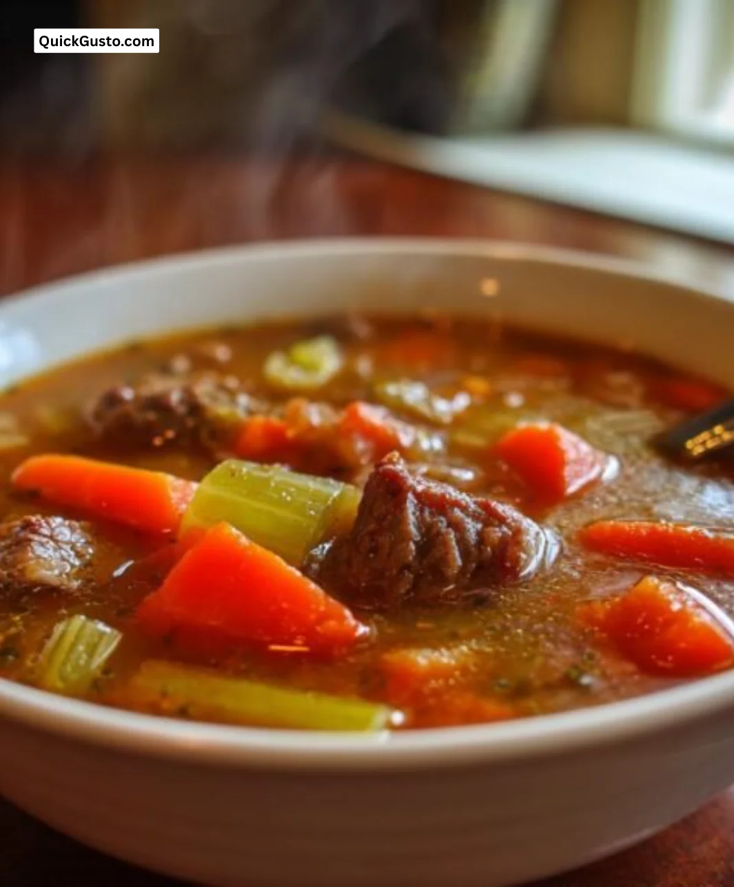 Delicious homemade vegetable beef soup in a bowl on a wooden table.