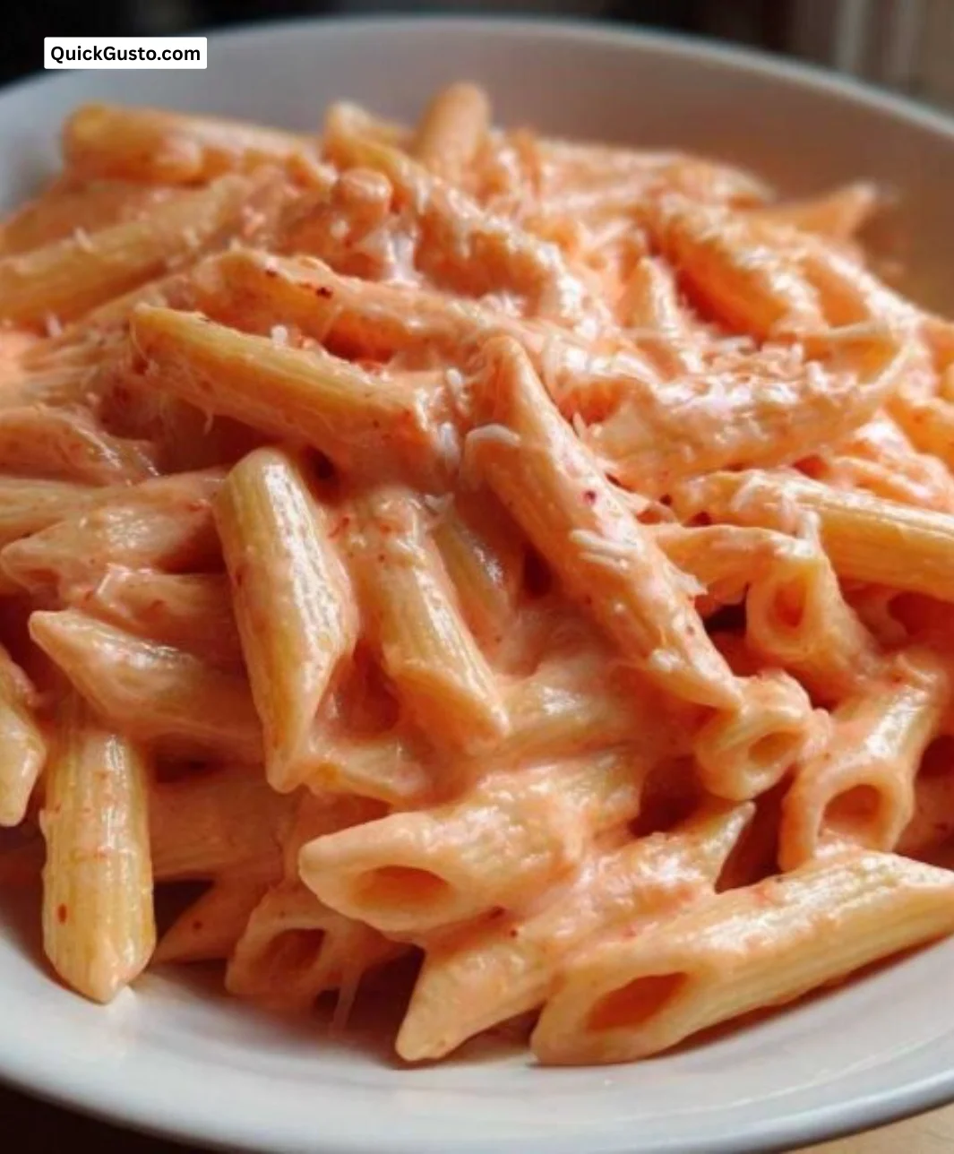 Delicious creamy pink sauce pasta in a bowl garnished with herbs and cheese.