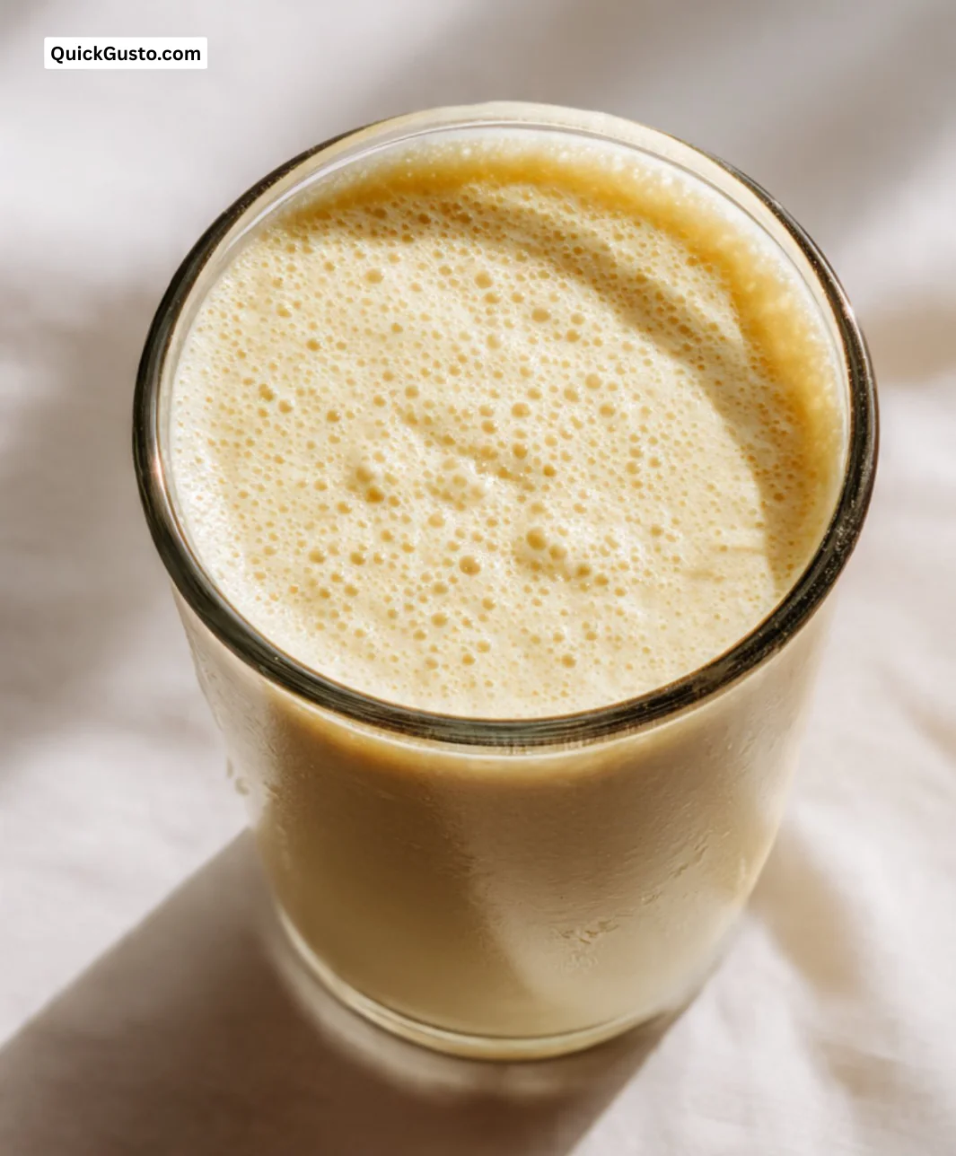 Delicious homemade banana smoothie in a glass with fresh bananas