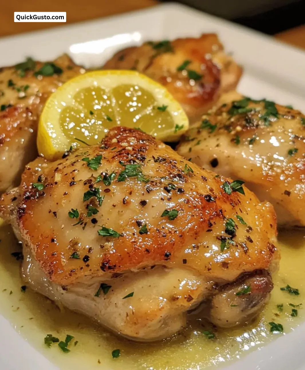 Garlic herb chicken thighs with zesty lemon butter sauce in a serving dish.
