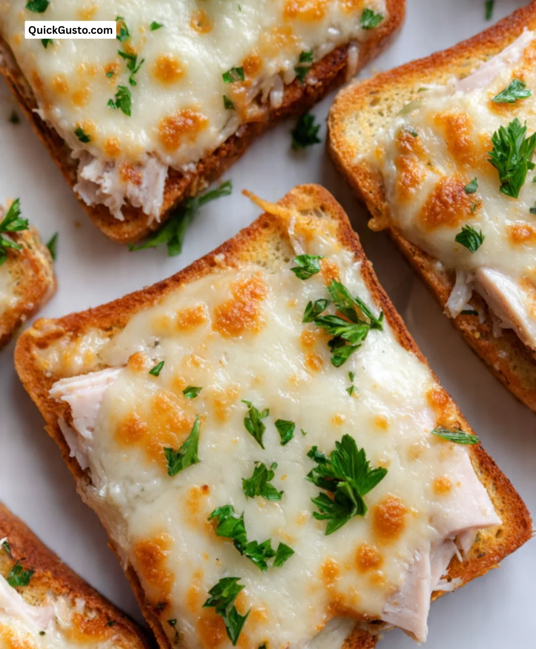 Slice of cheesy turkey toast topped with melted cheese and herbs