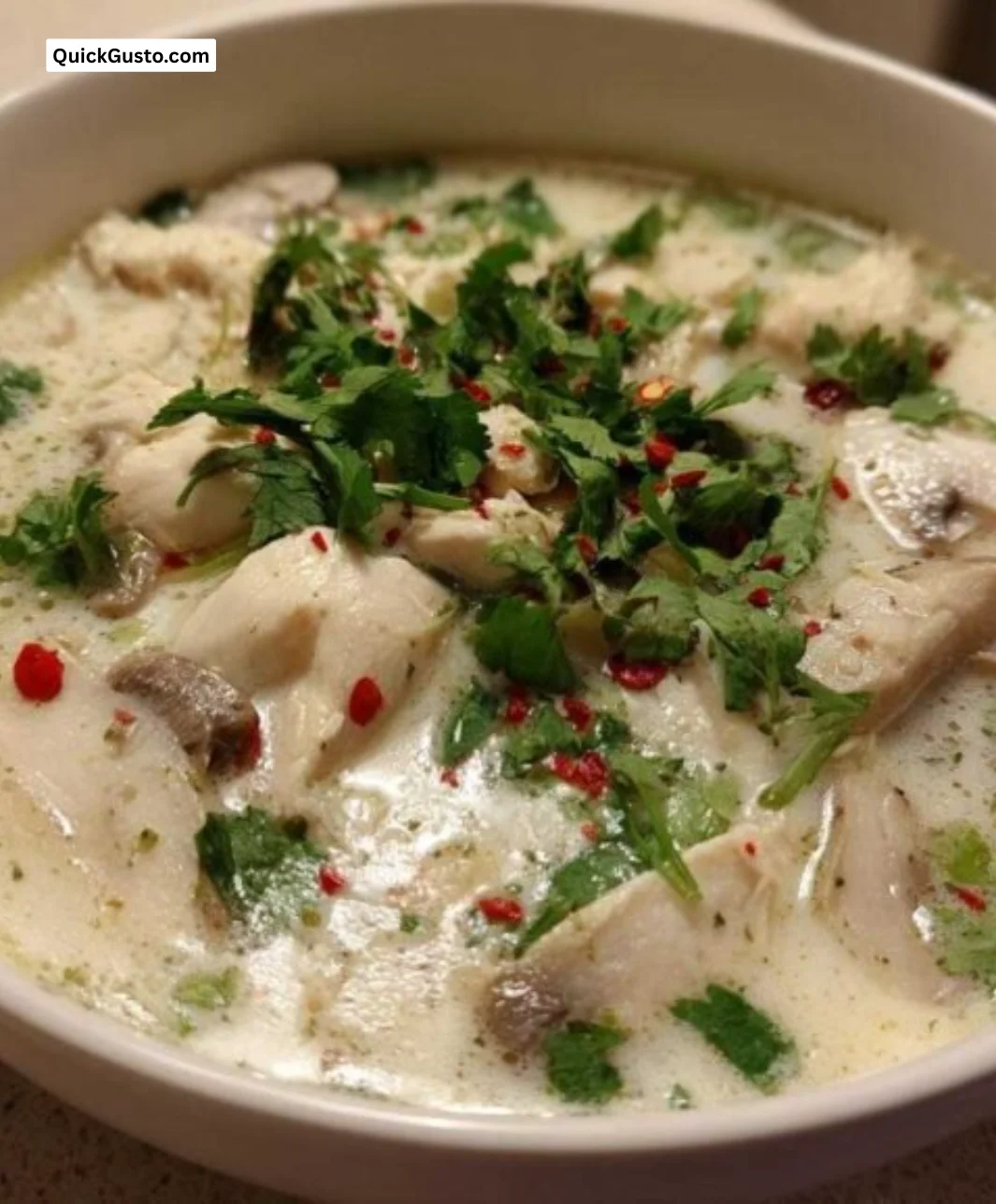 A bowl of delicious coconut soup garnished with fresh herbs.