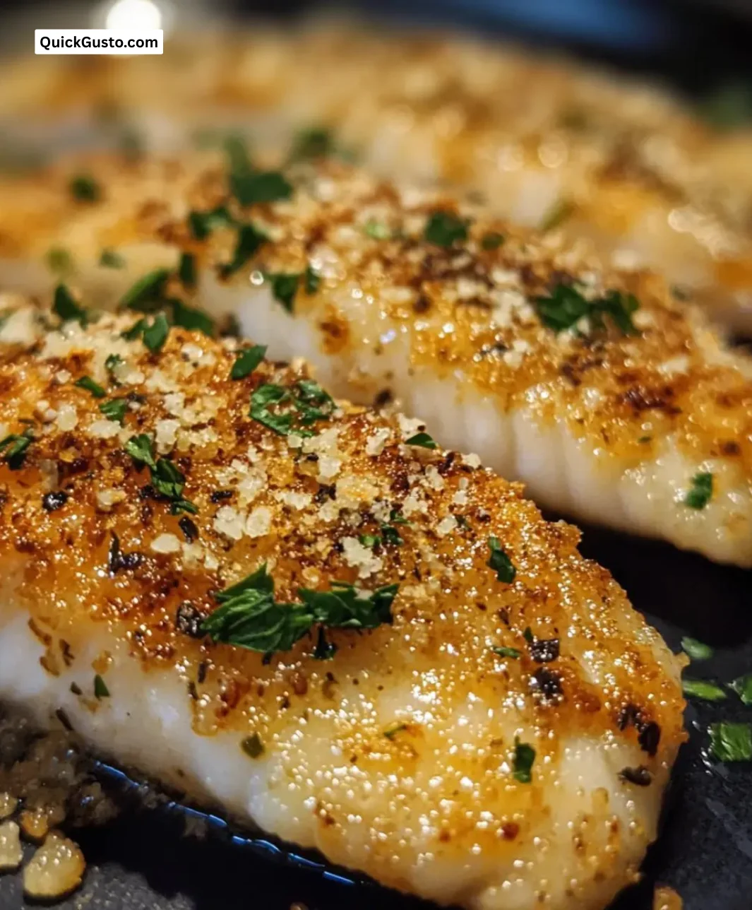 Crispy garlic parmesan fish fillets served on a plate with lemon and herbs