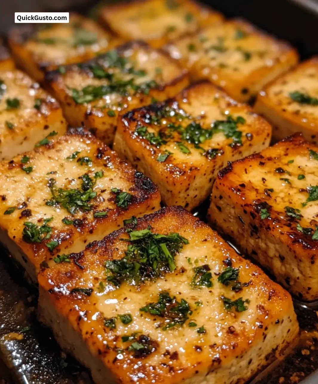 Easy garlic herb baked tofu ready to serve with fresh herbs on top