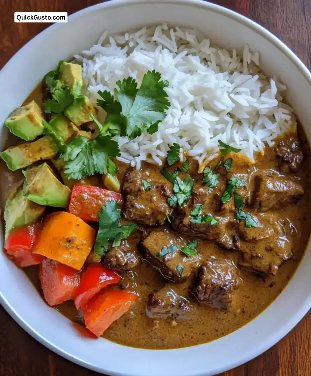 Bowl of Easy Instant Pot Coconut Tamarind Beef Curry with rice and herbs.