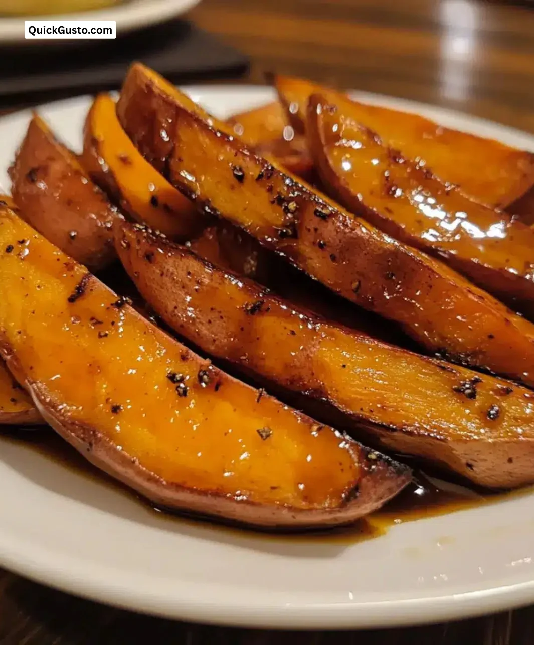 Easy maple glazed sweet potato wedges served on a plate with herbs