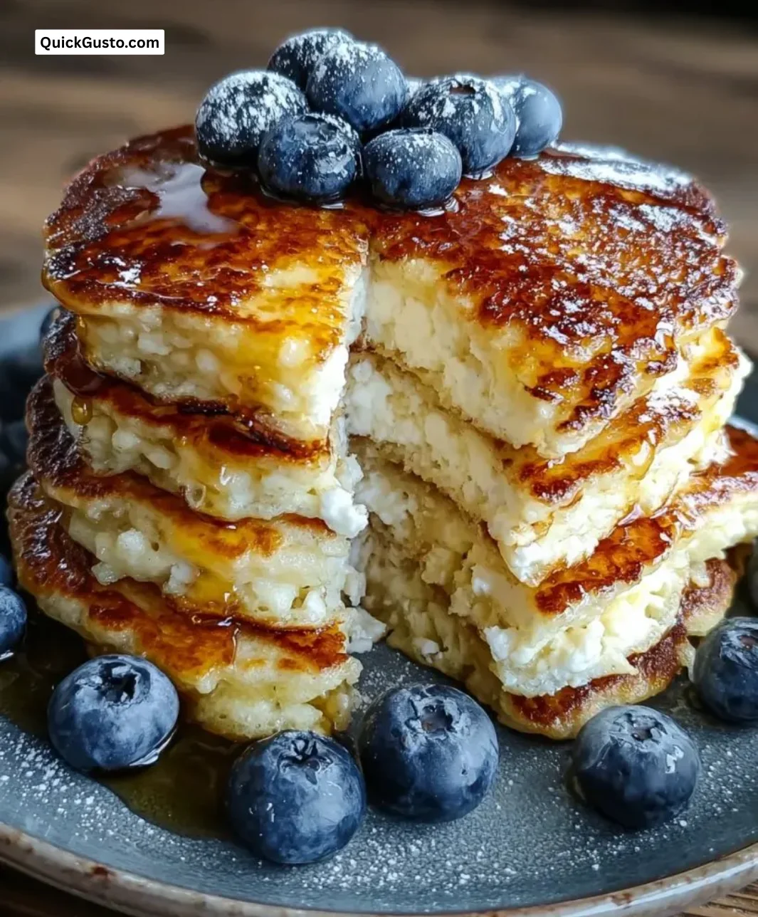 Fluffy cottage cheese pancakes stacked on a plate with syrup and fruit