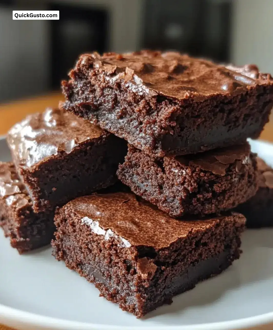 Stack of decadent dark chocolate tahini brownies on a white plate