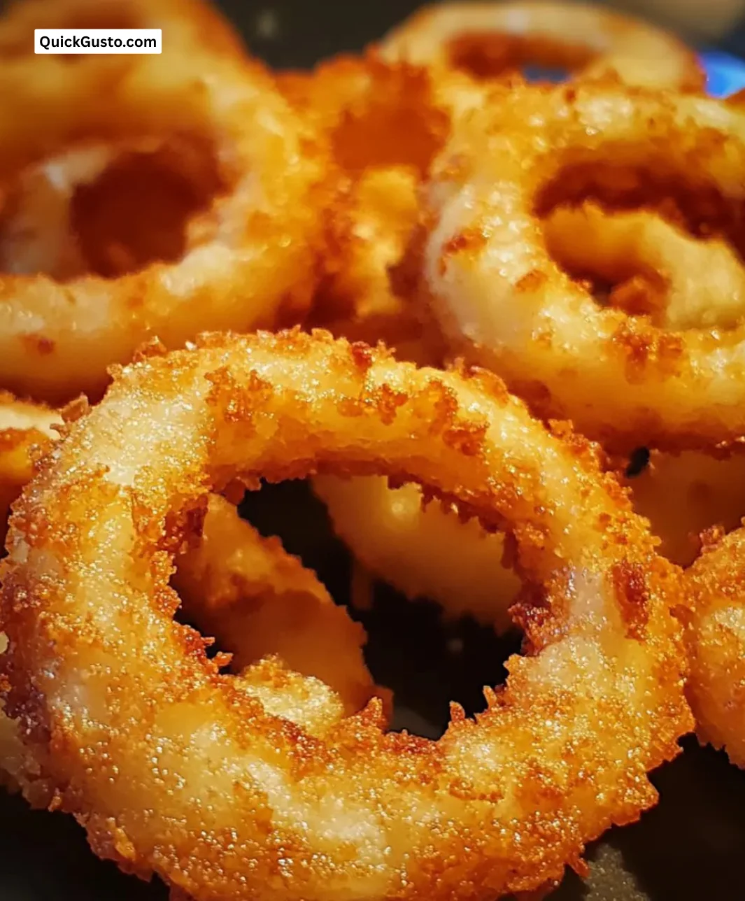 Plate of golden crispy onion rings, perfectly seasoned and deliciously crunchy.
