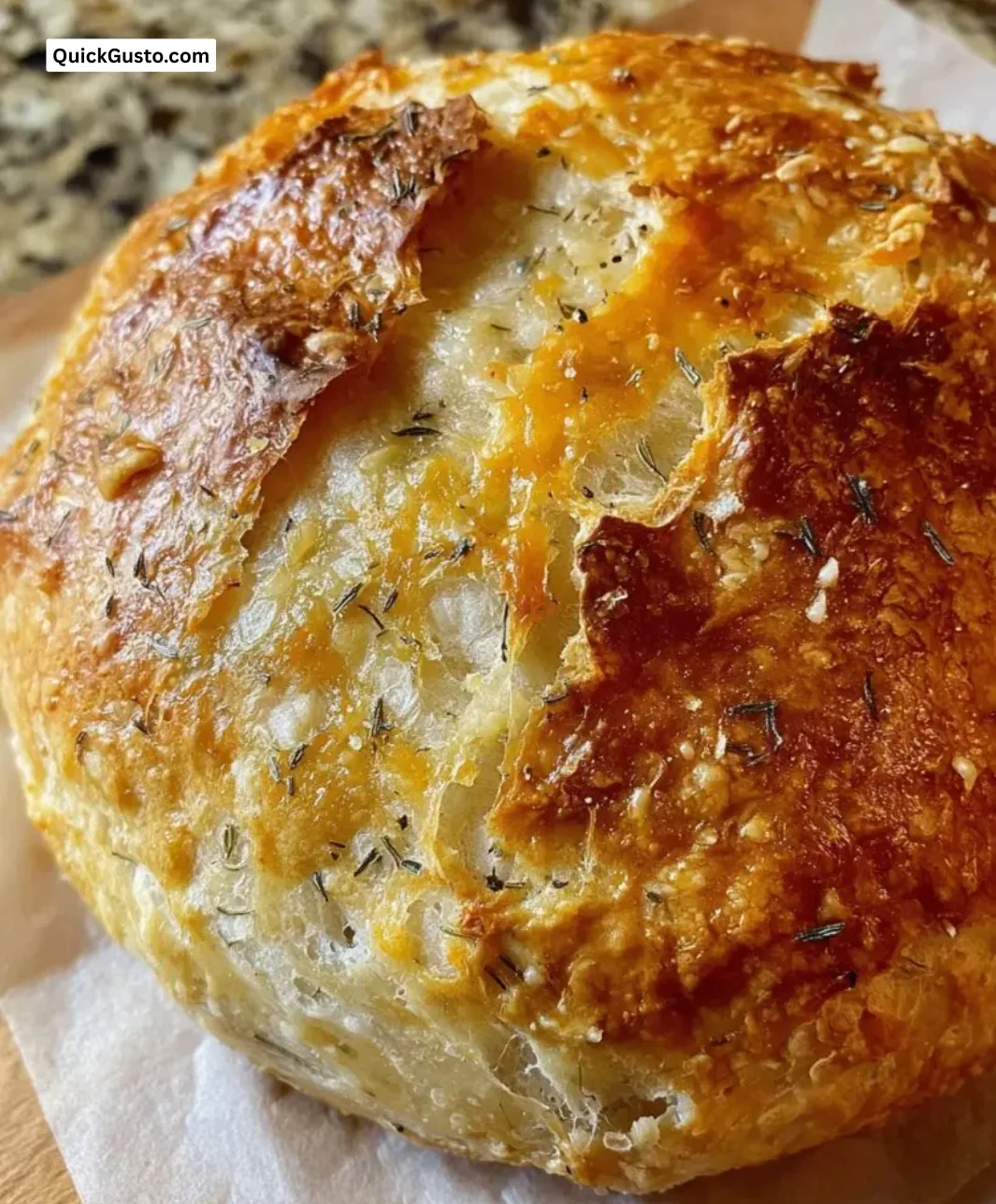 Freshly baked no-knead dill gouda artisan bread on a wooden cutting board