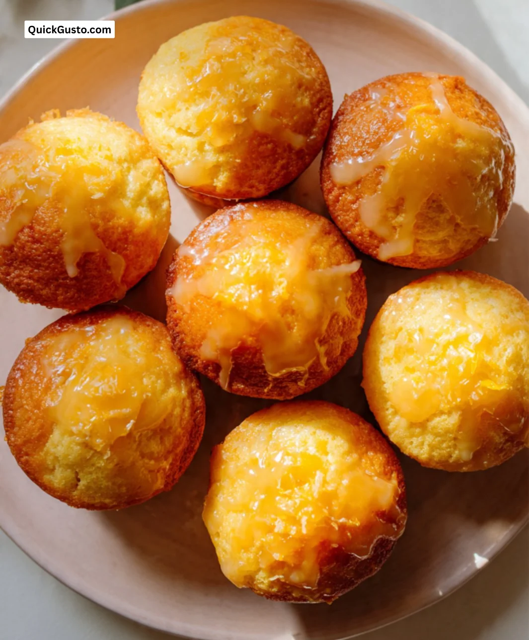 Freshly baked orange muffins with a golden crust and citrus glaze