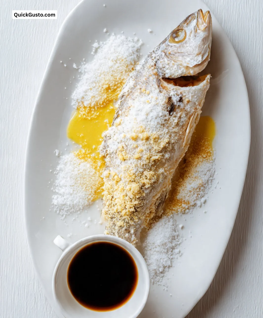 Delicious salt baked fish served with soy sauce hollandaise on a white plate.