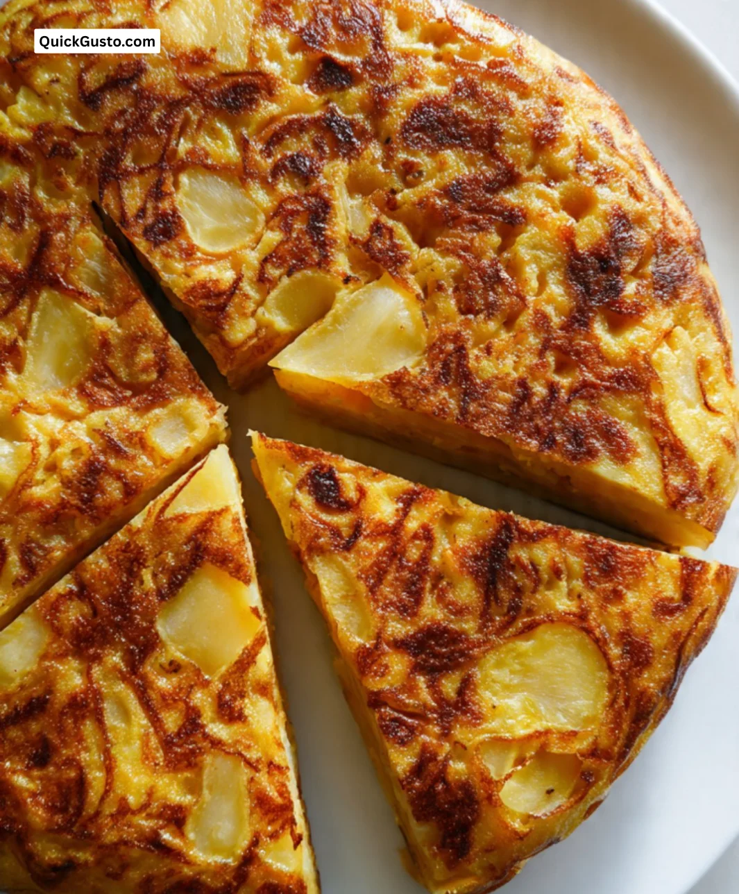 A traditional Spanish Omelette made with eggs, potatoes, and onions served on a plate.