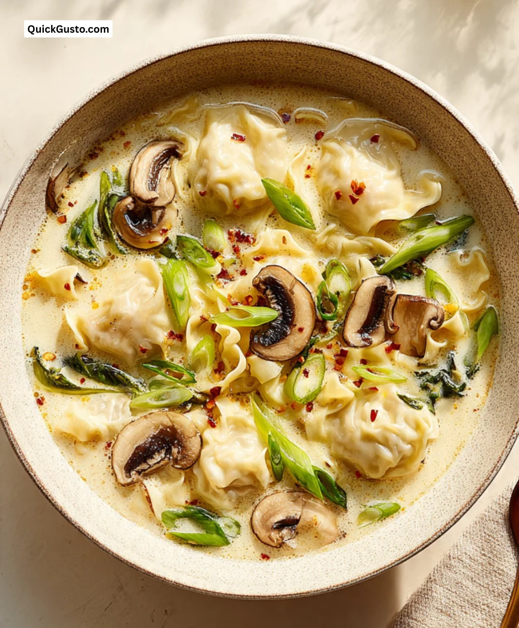 Bowl of wonton egg noodle soup topped with fresh herbs and veggies