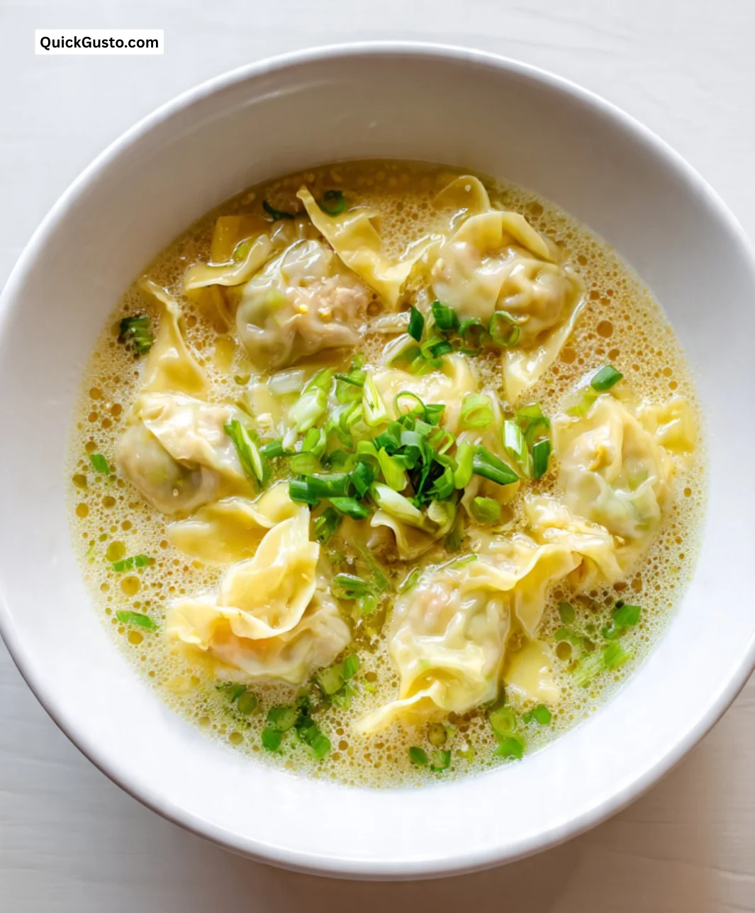 Bowl of wonton noodle soup with egg noodles and fresh ingredients