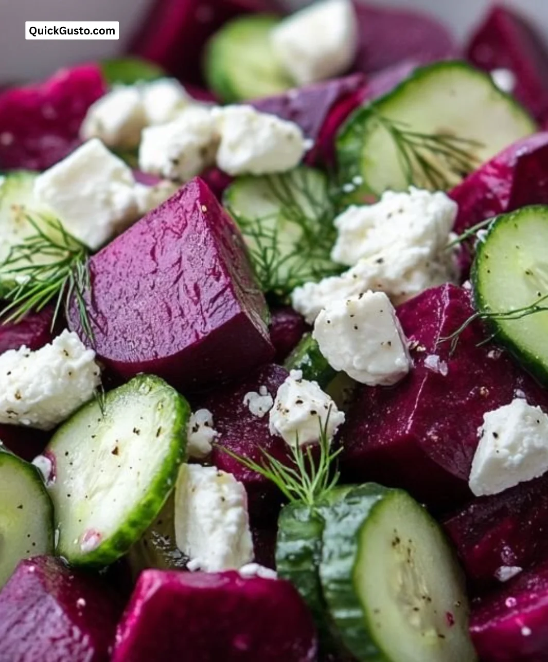 A colorful beet salad with feta cheese, fresh cucumbers, and dill garnish.