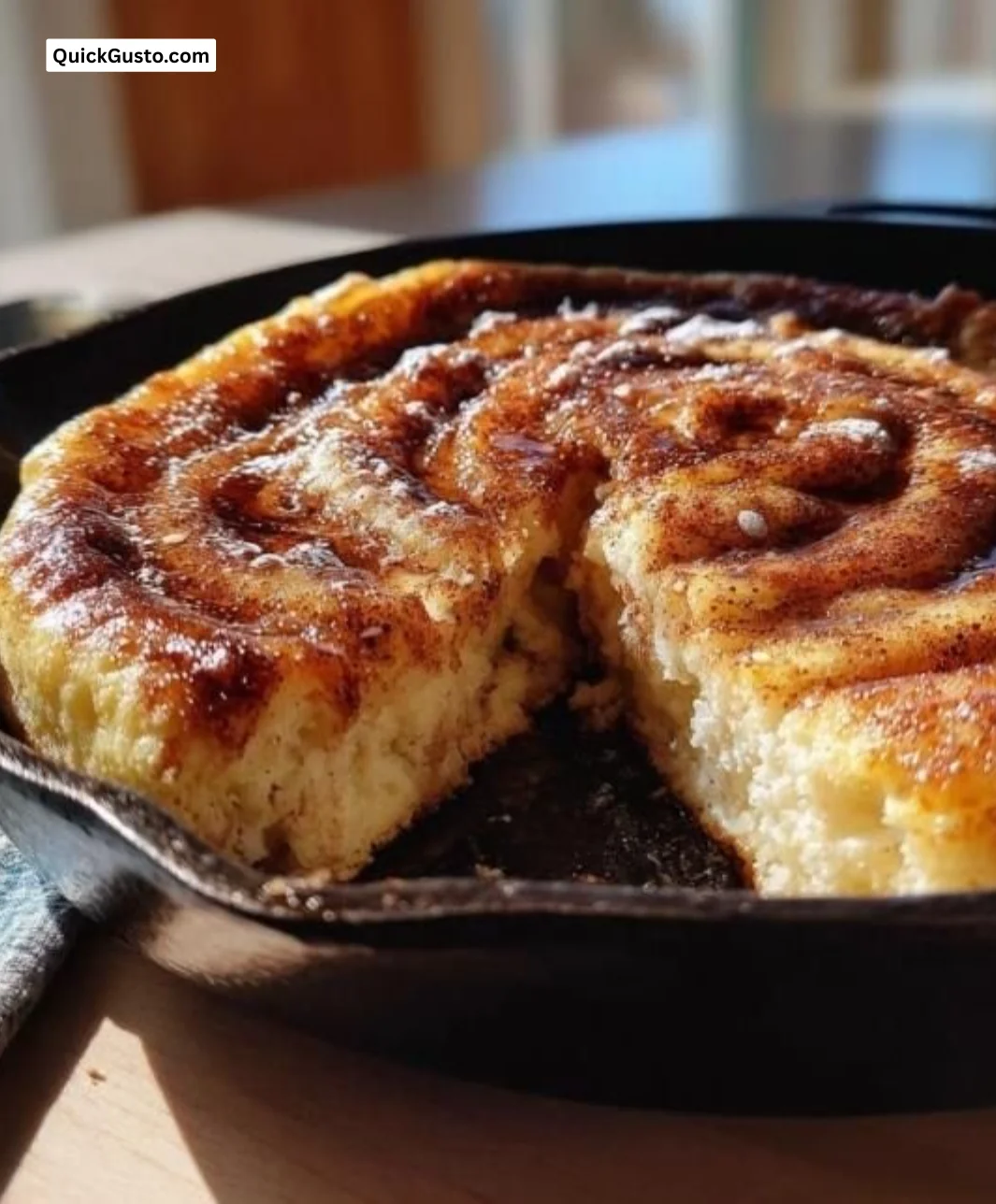 Cinnamon roll pancake skillet with drizzled icing and cinnamon topping