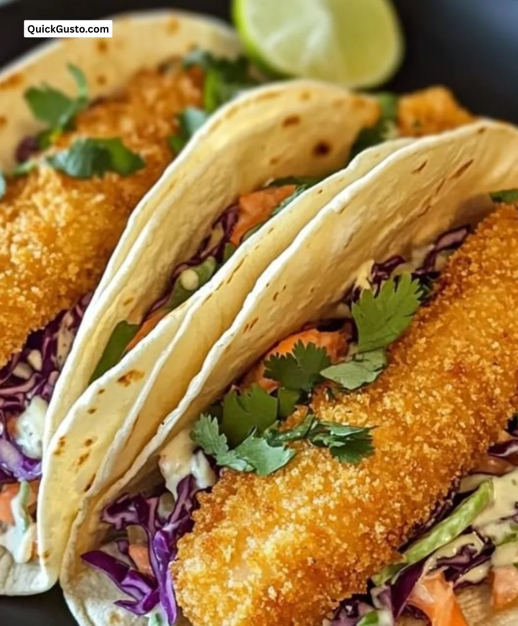 Crispy fish tacos topped with slaw and lime crema on a plate