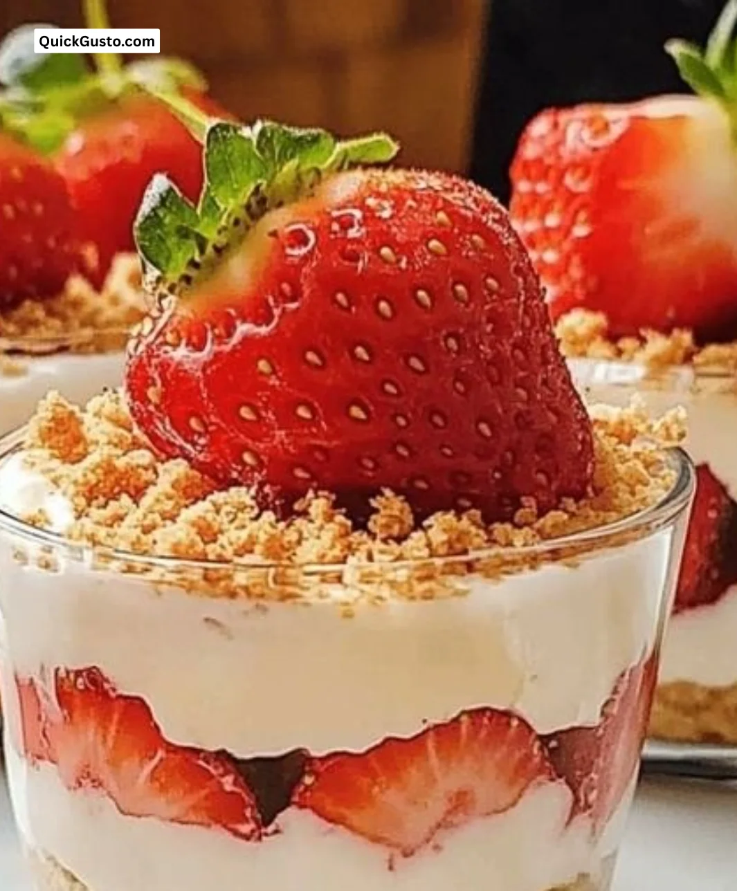 Easy no-bake strawberry cheesecake cups topped with fresh strawberries and cream.