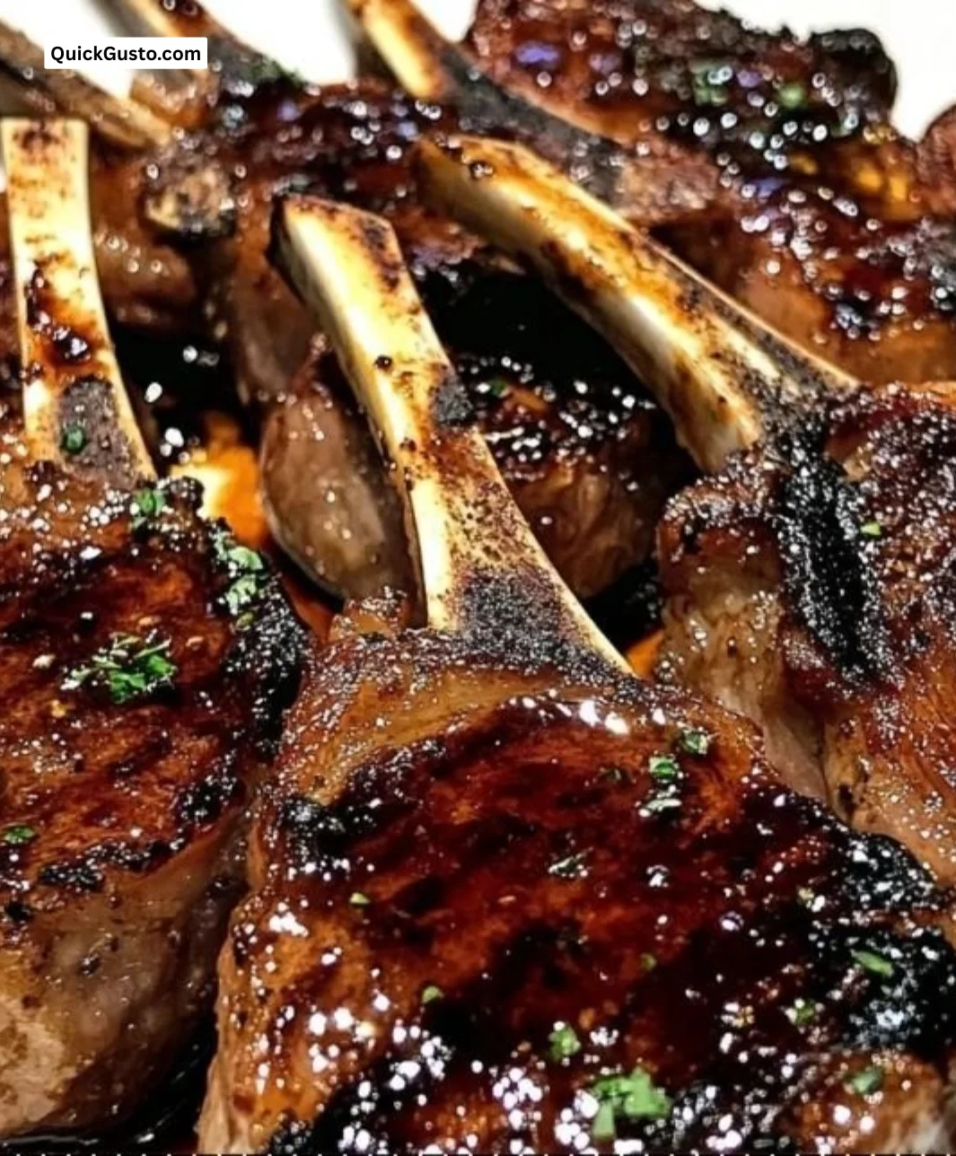 Honey garlic glazed lamb chops served on a plate with herbs.