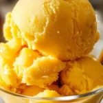 Bowl of homemade instant mango sorbet topped with fresh mango slices