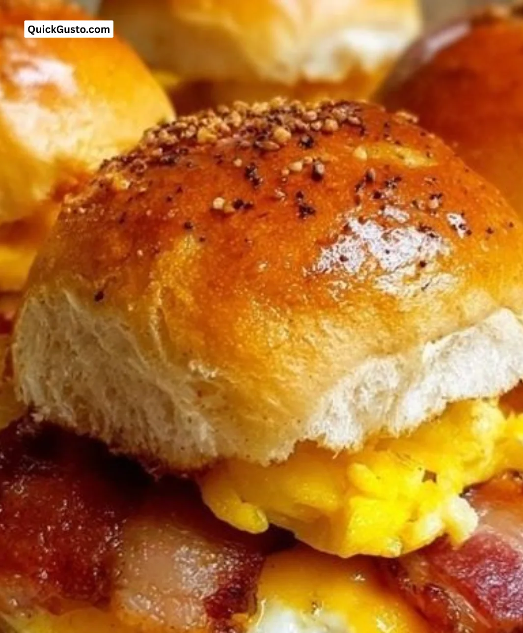 Mini breakfast sandwich sliders with eggs, cheese, and bacon on a platter