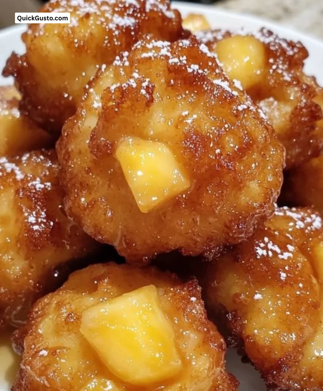 Golden-brown pineapple fritters served on a plate.