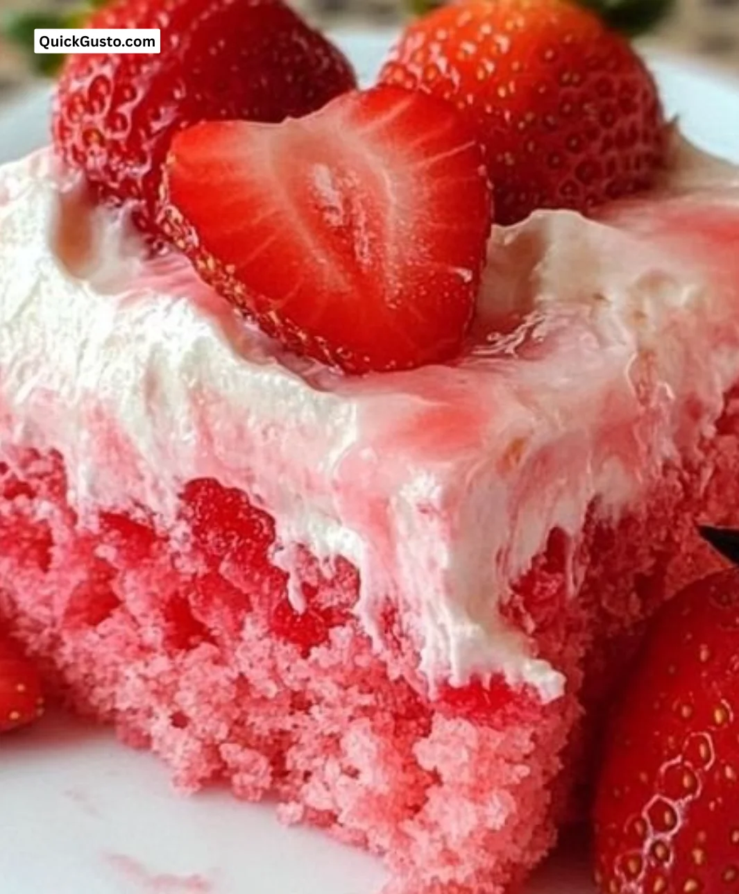 Slice of Strawberry Jello Poke Cake on a white plate with fresh strawberries