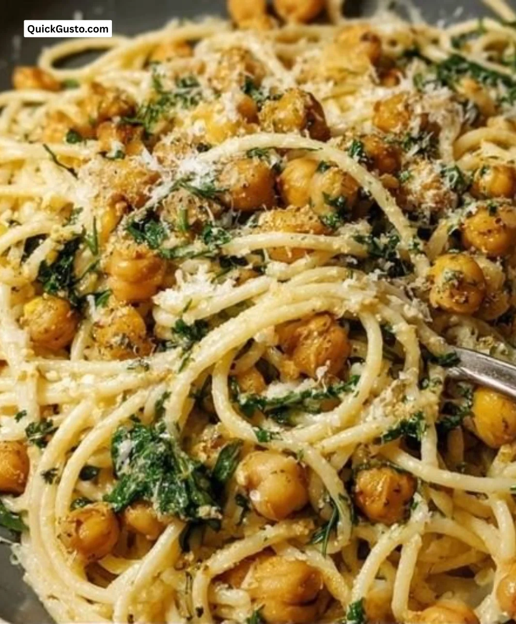 Bowl of zesty lemon chickpea pasta garnished with fresh herbs and slices of lemon.