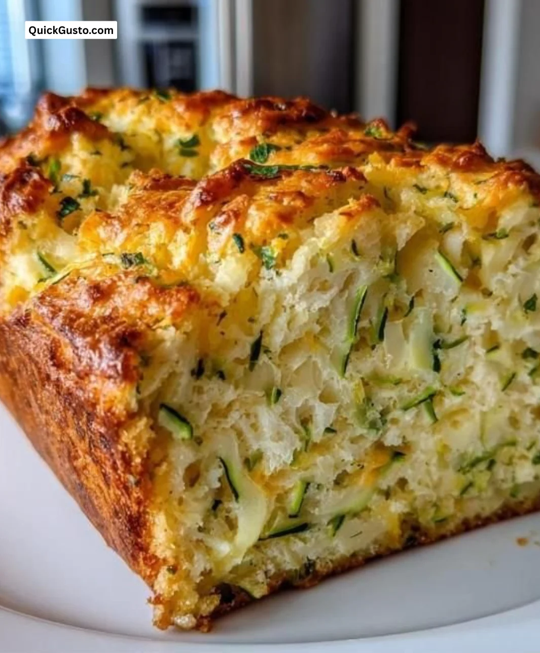 Freshly baked Zucchini Cheddar Herb Loaf on a wooden cutting board.