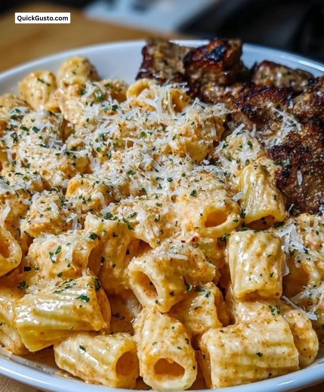 Cajun steak served with cheesy rigatoni parmesan, a delicious fusion dish.