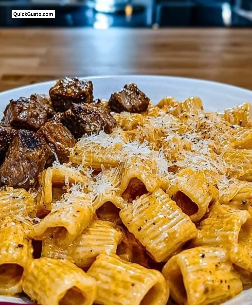 Cajun steak served with cheesy rigatoni parmesan on a plate.