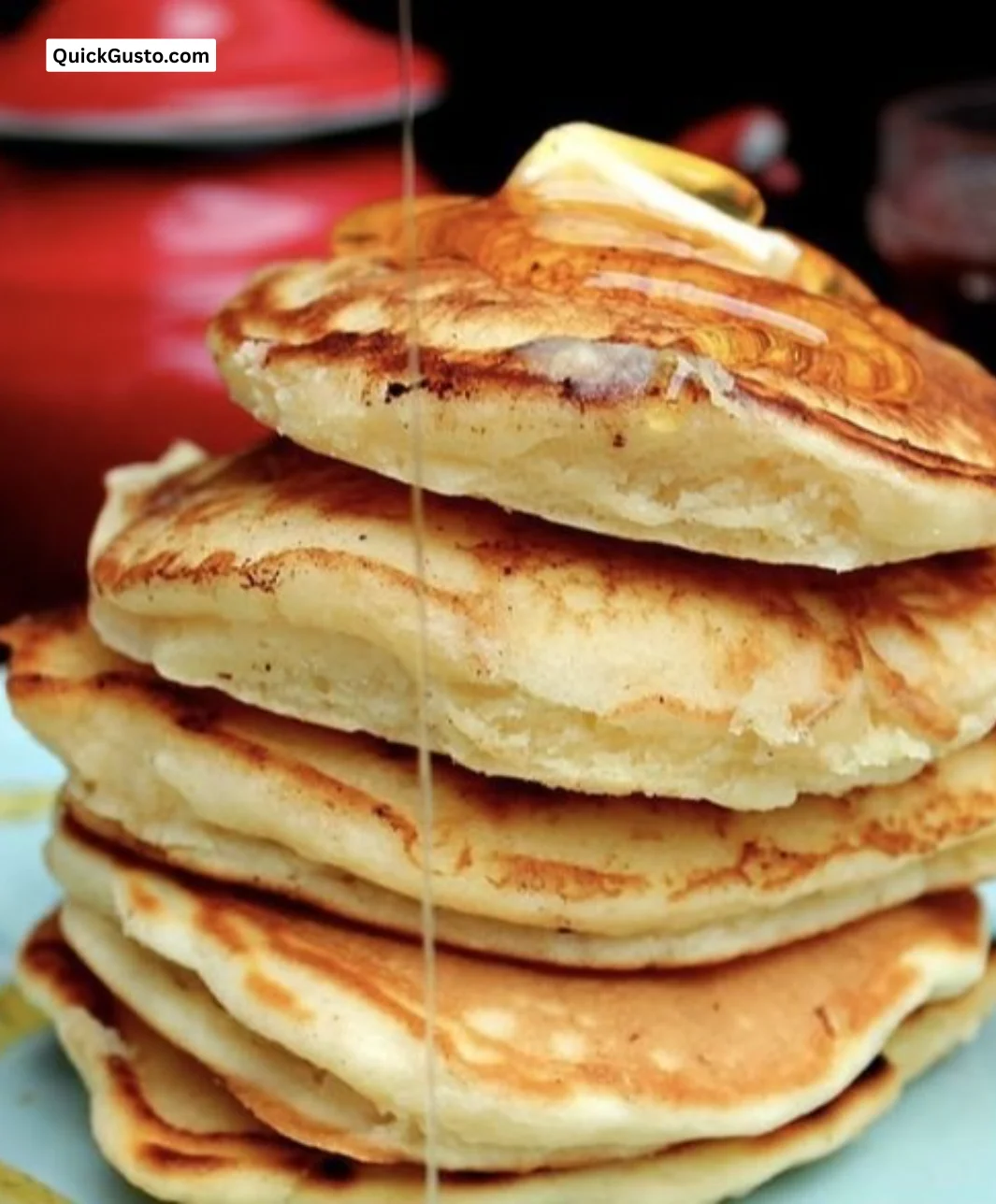Delicious Cloudy Buttermilk Pancakes stacked on a plate with syrup and berries