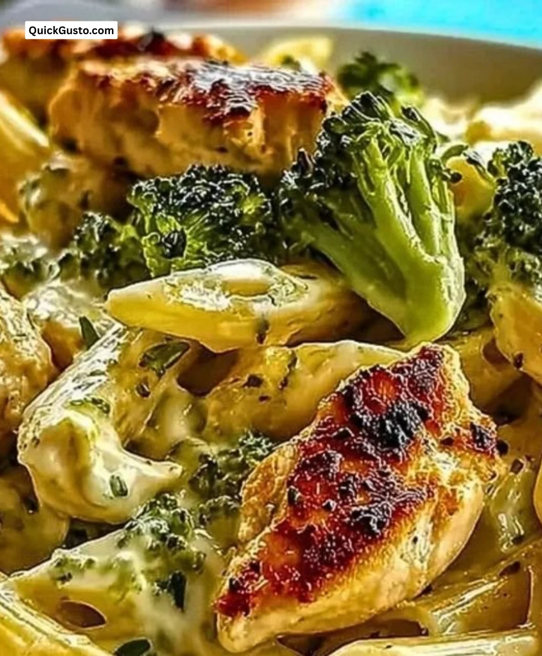 Creamy broccoli and chicken penne pasta dish garnished with fresh herbs