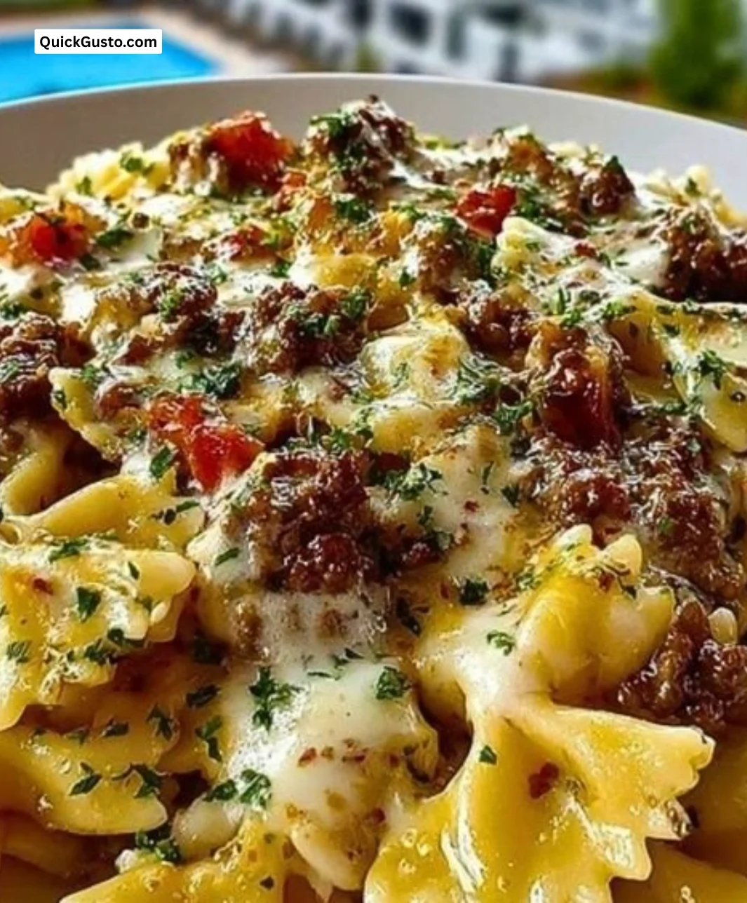 Creamy ground beef bowtie pasta served in a bowl, garnished with herbs