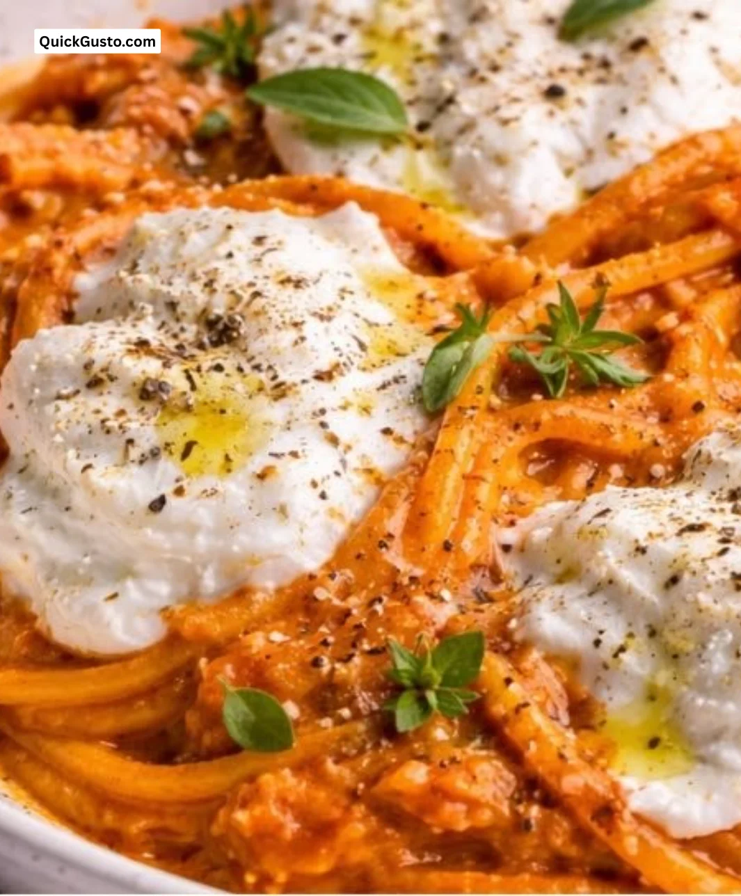 Creamy red pepper pasta with burrata and fresh herbs in a bowl.