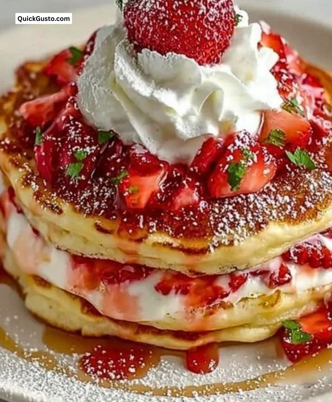 Fluffy strawberry cheesecake pancakes stacked and topped with fresh strawberries