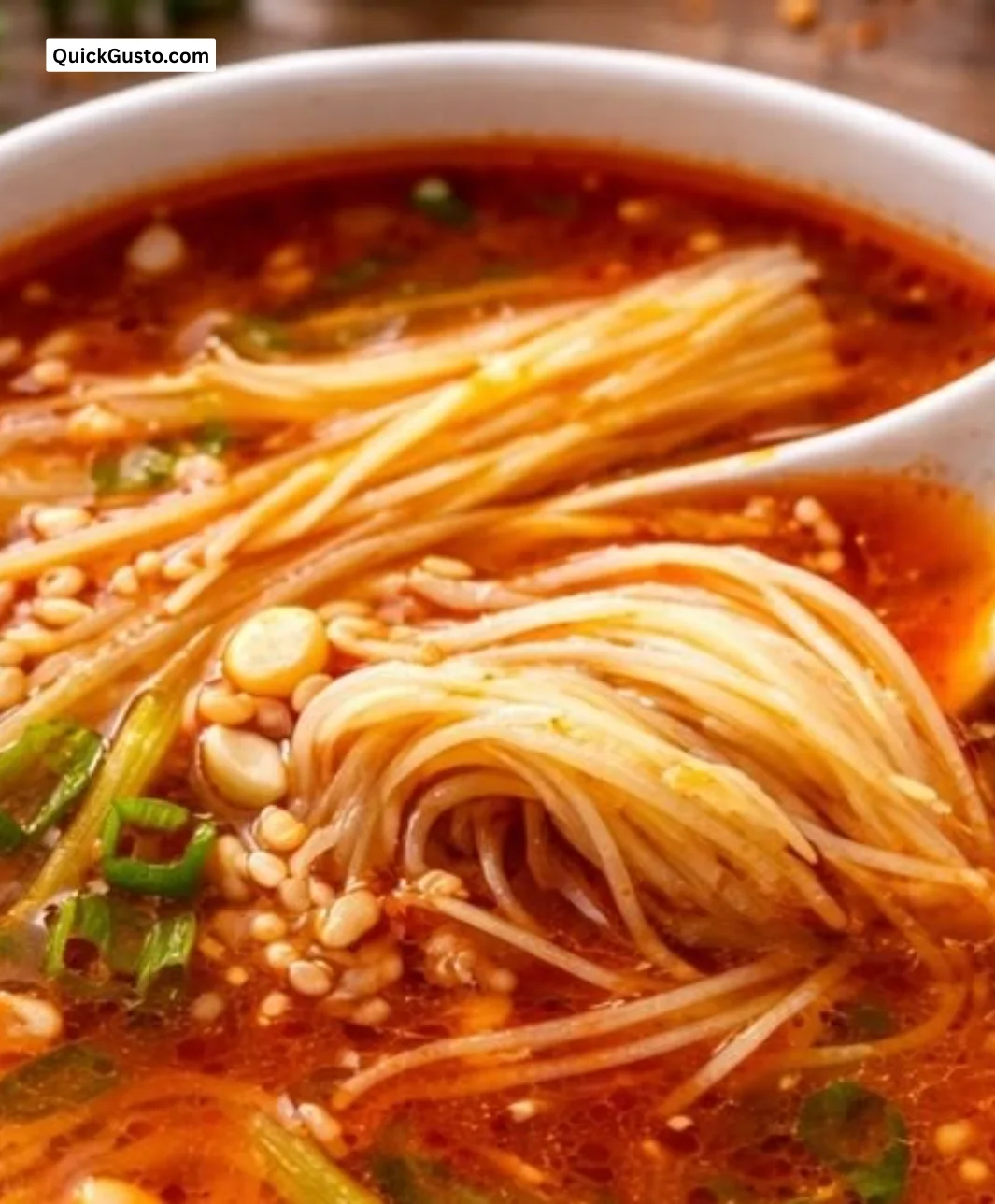 Bowl of hearty tomato enoki mushroom soup garnished with fresh herbs.