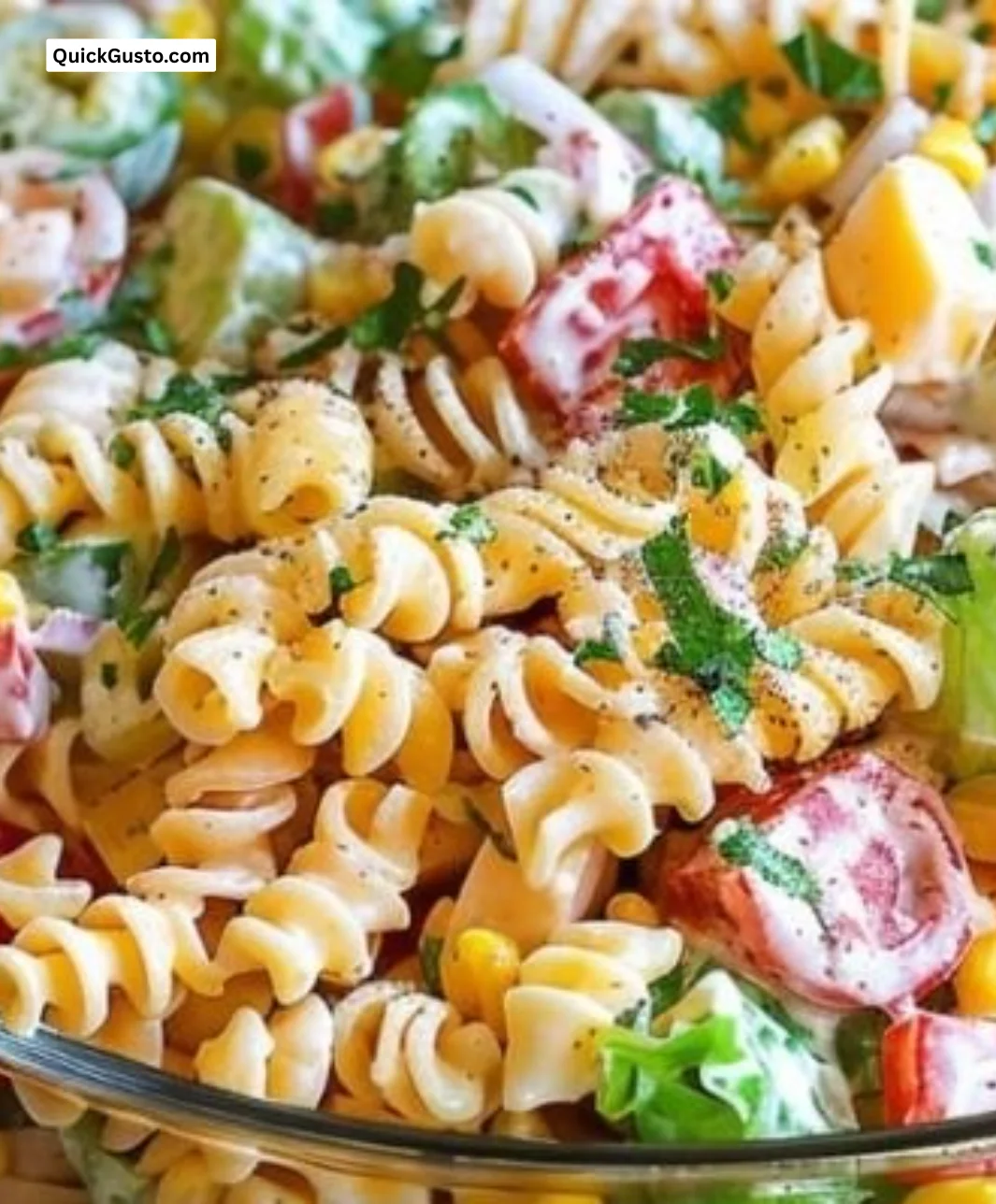 Colorful layered pasta salad with fresh vegetables and dressing