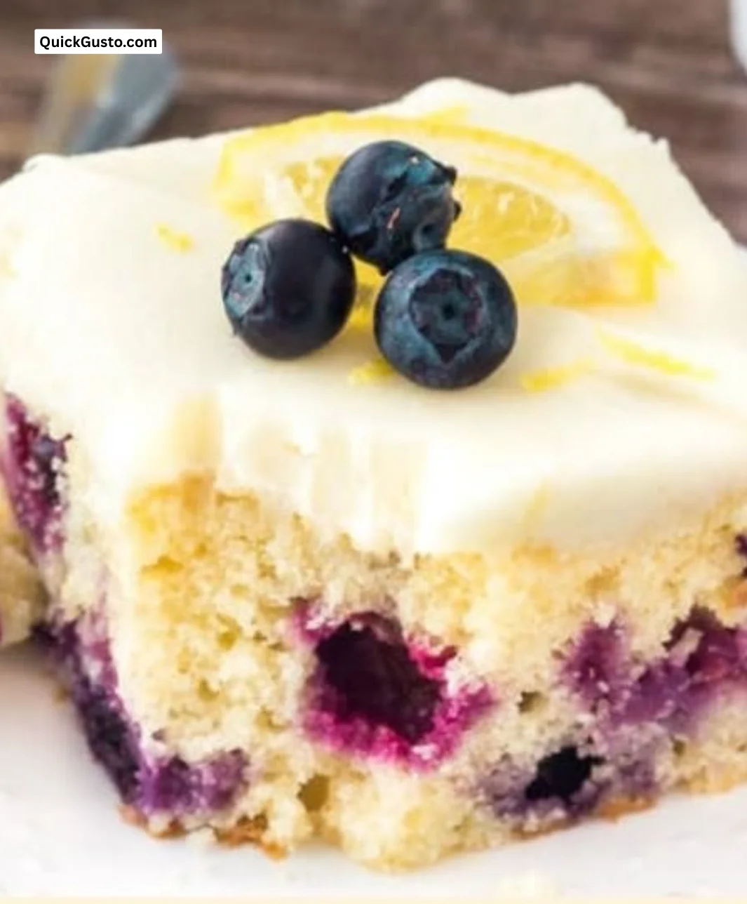 Sliced lemon blueberry cake topped with fresh blueberries and lemon zest