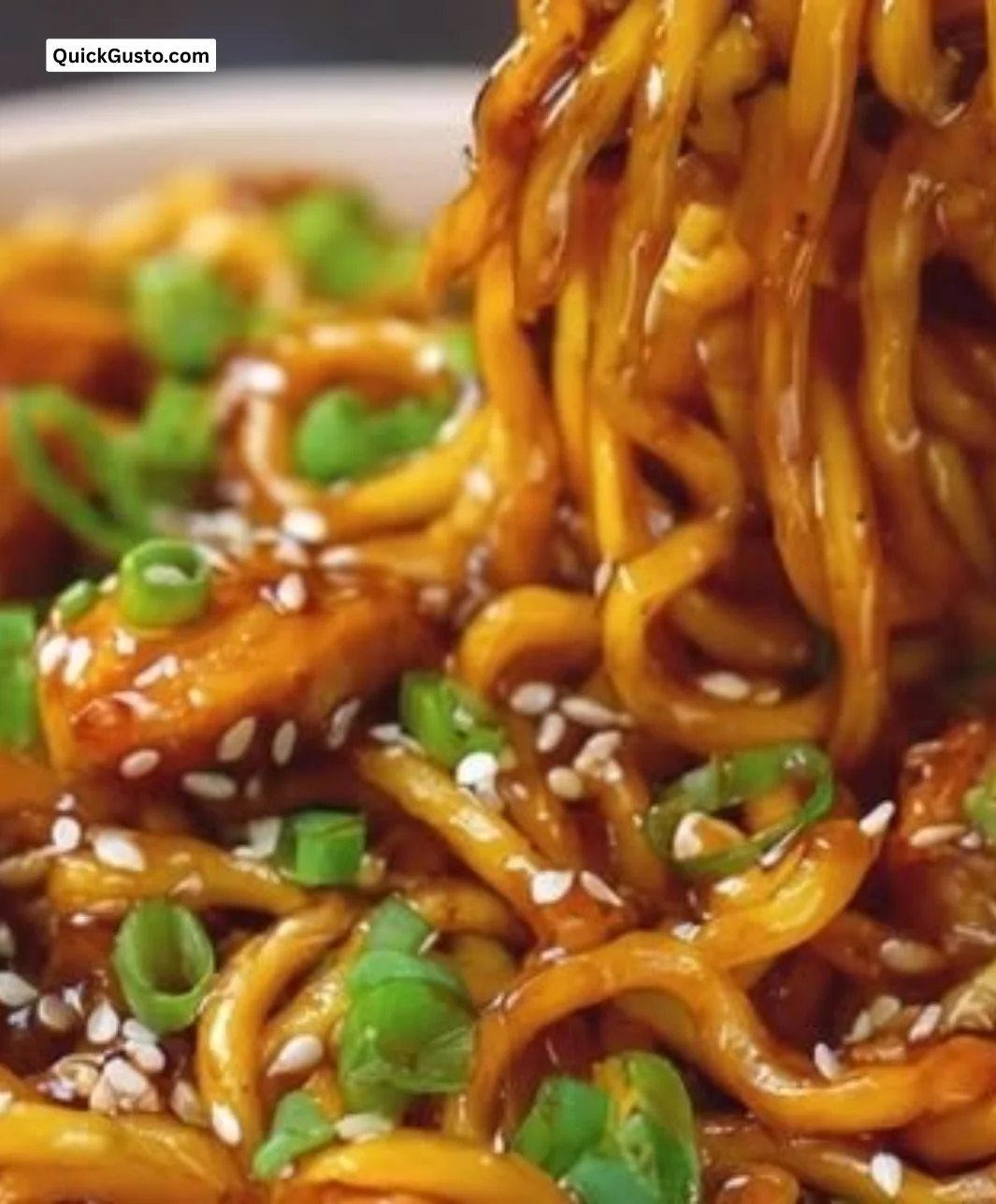 Plate of sticky chicken noodles garnished with fresh herbs